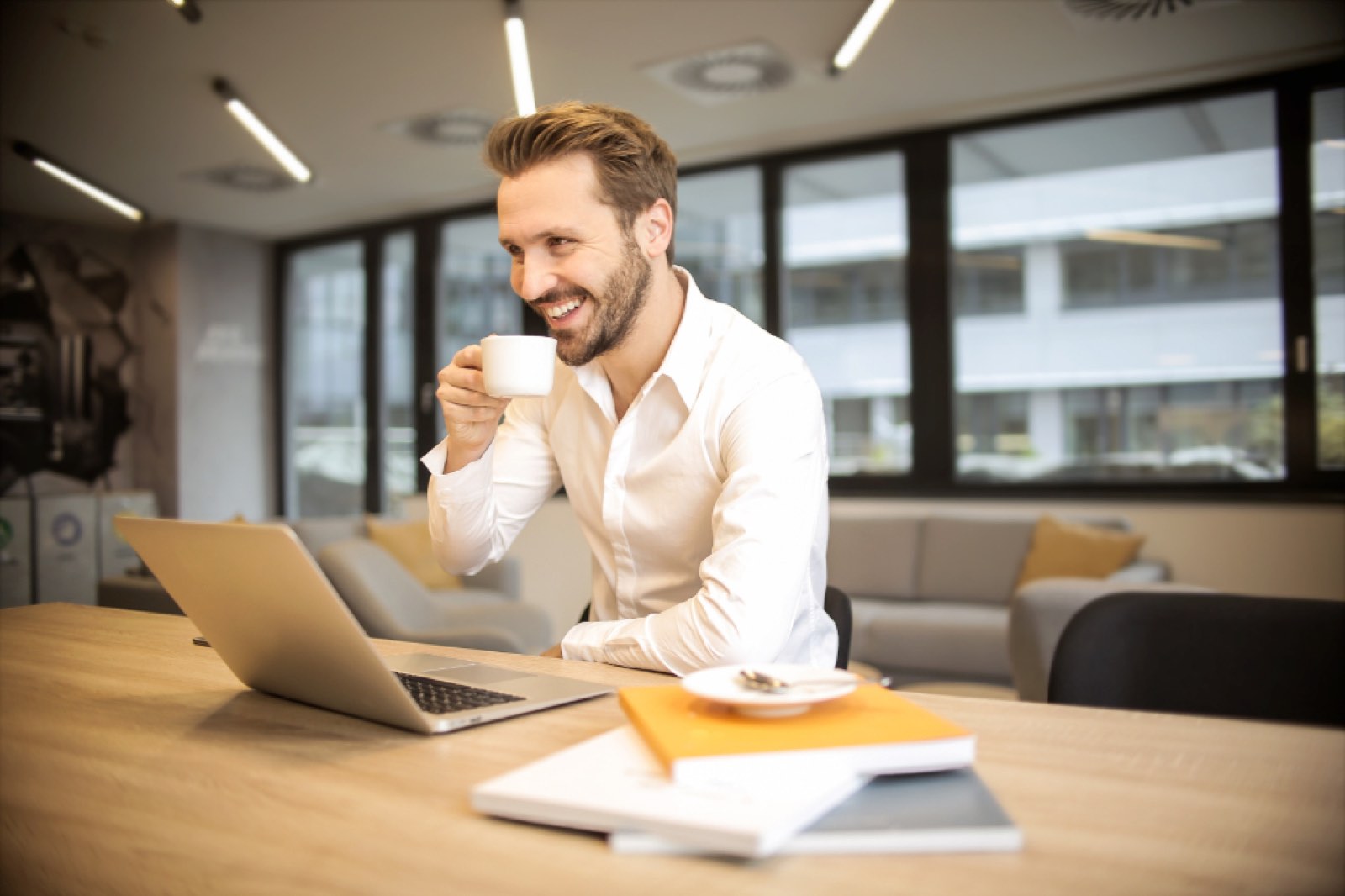 A man laughing with coffee at his laptop