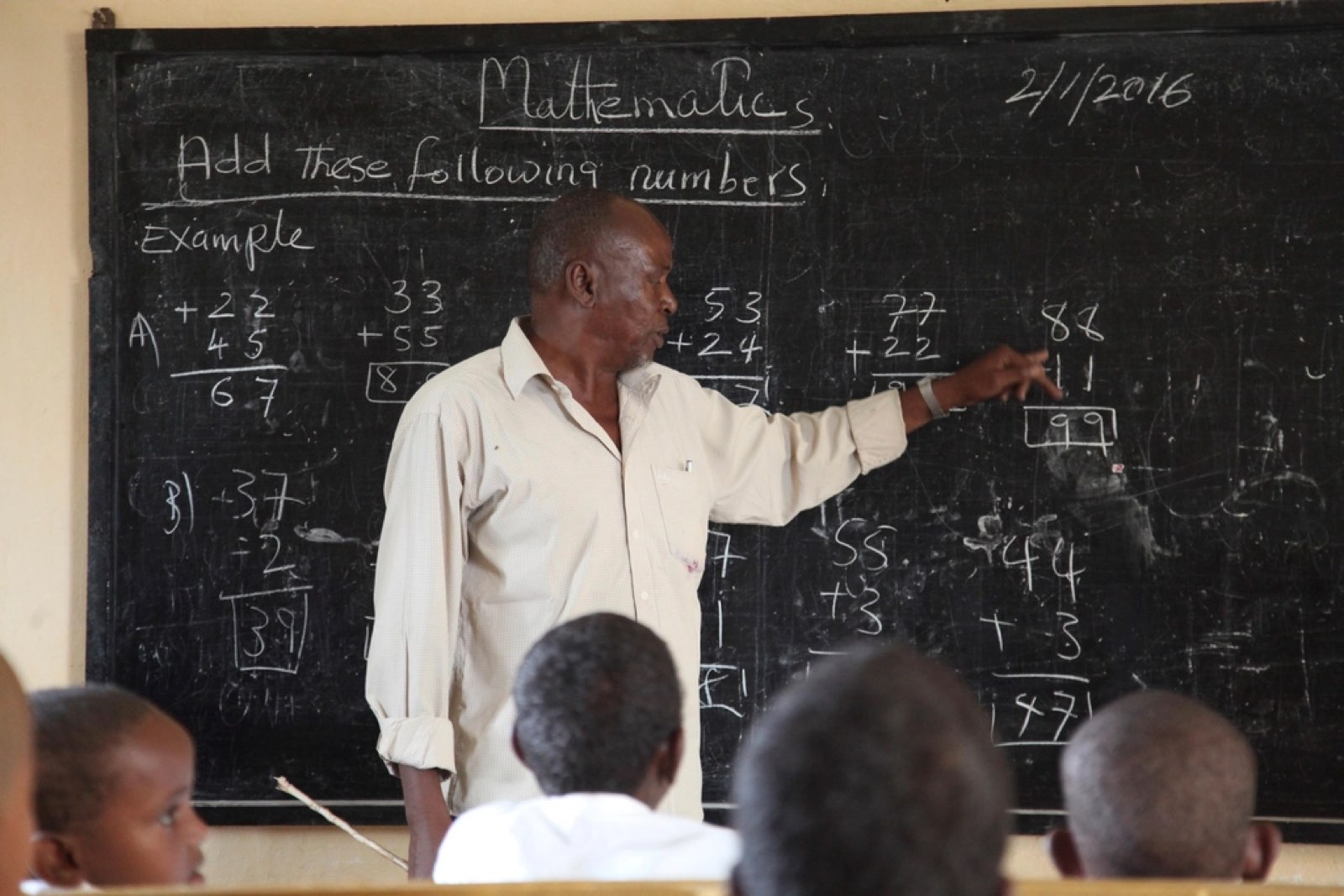 A teacher explaining maths at a blackboard